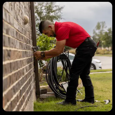 A man repairs an outdoor faucet.