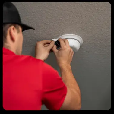 A man installs a white dome-shaped light fixture on a textured ceiling
