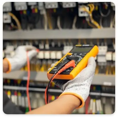 An electrician tests a circuit with a multimeter, showing surge protection services