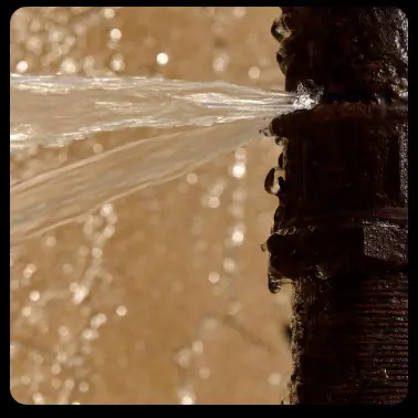 A rusted pipe is leaking with water gushing from its side