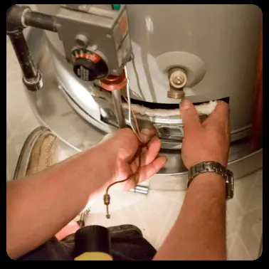 technician repairing a water heater, presumably to ensure it works efficiently