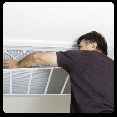 A man replaces an air filter in a vent