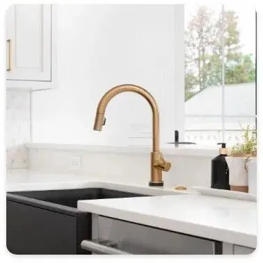 A modern kitchen features a gold faucet over a dark sink.