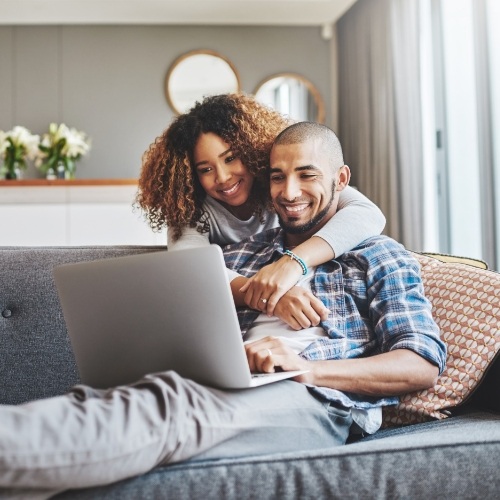 couple looking at laptop while sitting on the couch